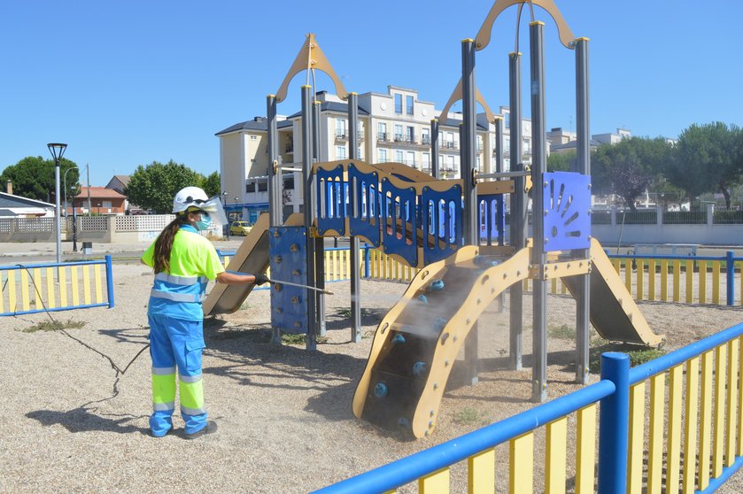 Una operario de limpieza desinfecta un parque infantil de la localidad
