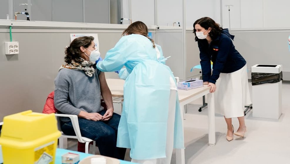 Una mujer, vacunándose contra el coronavirus mientras habla con Díaz Ayuso / Comunidad de Madrid